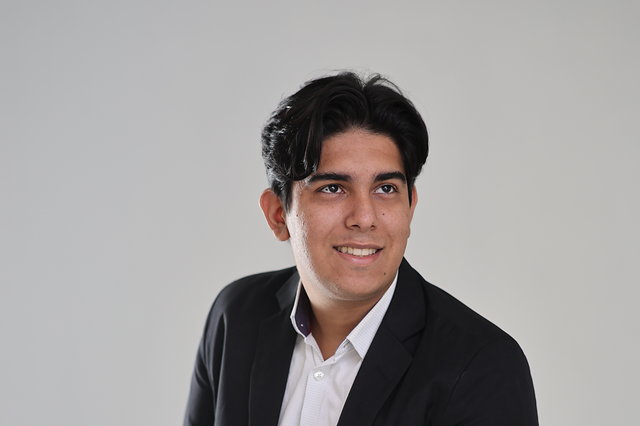 Victor Carvalho, candidato a Deputado Estadual por Mato Grosso, de blazer preto sobre camisa branca, sorrindo para a câmera.
